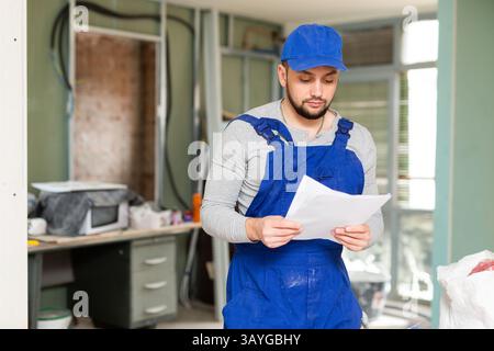 Foreman reading papers on indoor construction site Stock Photo