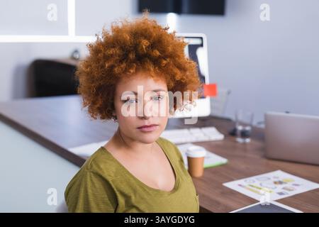 Woman working on computer and laptop in modern office with charts, coffee cup and water glass Stock Photo