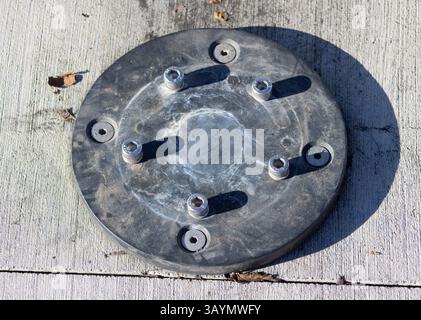 circular metal plate with screws on ground Stock Photo