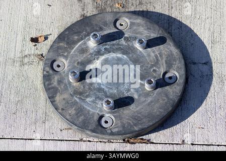 circular metal plate with screws on ground Stock Photo