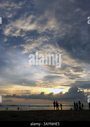 The image captures a stunning sunset over the ocean. The sky is painted in warm hues of orange and yellow, blending into the darker tones. Stock Photo