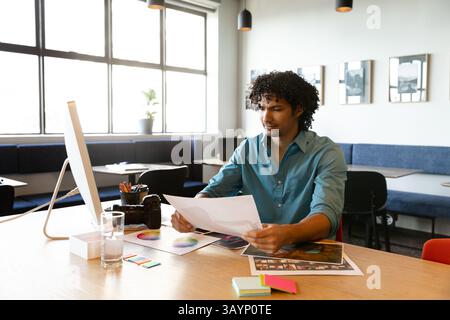 Man reviewing photos and color swatches alongside DSLR camera on creative studio table, copy space Stock Photo