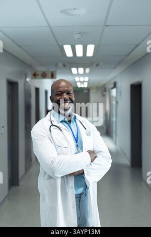 Mature African American male doctor smiling in hospital corridor, with stethoscope and ID badge Stock Photo