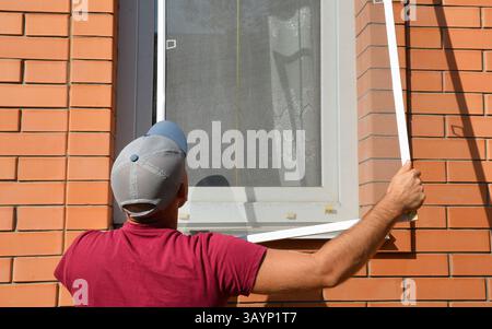 Install Window Fly Screen. A bug screen is a mesh-embedded frame that has been demonstrated to keep out insects such as mosquitoes, flies, and other p Stock Photo