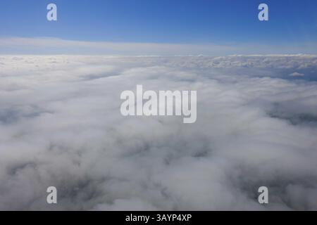 The flight over the vast sea of clouds under a blue sky and bright horizon Stock Photo