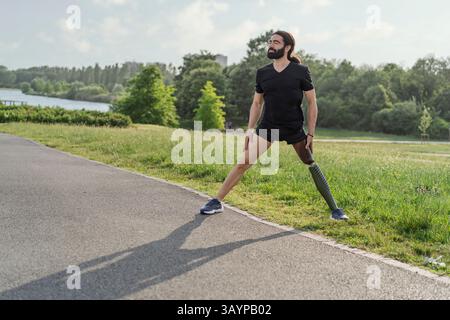 Athlete with prosthetic leg stretching outdoors before a workout, showing determination and adaptation. Concept of fitness, resilience, flexibility an Stock Photo
