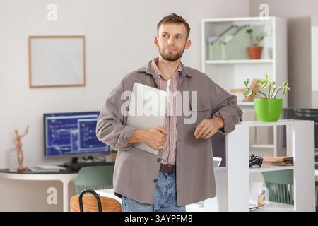Young bearded programmer with laptop in office Stock Photo