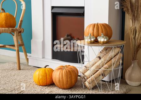 White fireplace, basket with wooden logs and pumpkins in autumn living room, closeup Stock Photo