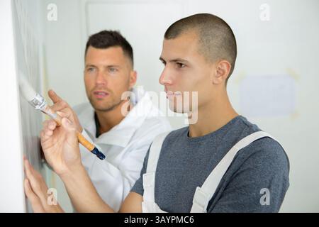 apprentices learning how to paint with a thick brush Stock Photo