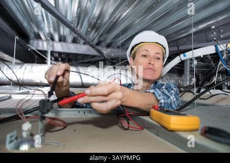 female electrician testing charge to spotlight Stock Photo