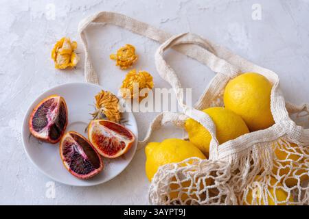 Lemons and oranges in a string bag on a white background Stock Photo