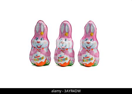 Germany Berlin April 21, 2025. Three chocolate bunnies Kinder Surprise. Pink and white eggs. Stock Photo