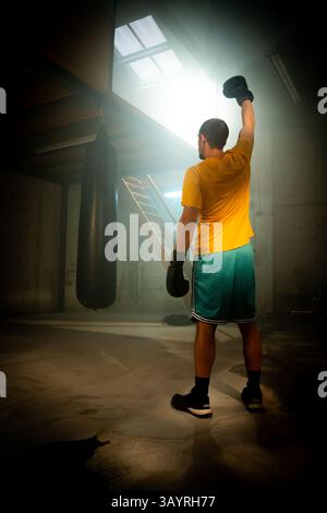 A determined boxer engages in intensive training within a dimly lit, gritty gym environment Stock Photo
