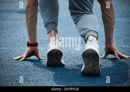 Close up of back view of mans feet in sport shoes running on blue running track. Season workout, crossfit and training. Close up. Stock Photo