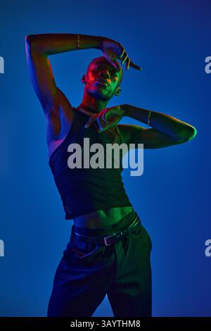 Stylish young man expresses creativity with dynamic movements in vivid lighting arrangement. Stock Photo