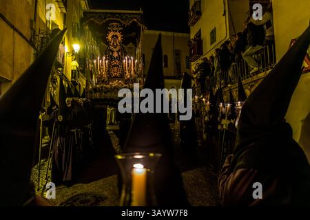 The paso Nuestra Señora de la Soledad, surrounded by burning candles and white flowers, moves through the narrow Calle Alonso de Ojeda. At the sight of the Mater Dolorosa, the angry crowd of the Good Friday procession falls silent. Cuenca, Castilla-La Mancha, Spain. The paso, created in 1947 by Federico Coullaut-Valera, is carried by 30 men of the Venerable Hermandad de Nuestra Señora de la Soledad de San Agustín. During Semana Santa in Cuenca, 33 Hermandades take part in eleven processions through the city during Holy Week. Stock Photo