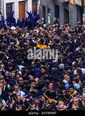 Turbas de Cuenca in purple robes make a deafening noise with their drums (tambores) and tin trumpets (clarines) at the head of the Camino del Calvario procession, which passes through Cuenca on Good Friday. Many people hit each other with crossed drumsticks and create the sound known as palilladas. Plaza Mayor, Cuenca, Castilla-La Mancha, Spain Stock Photo