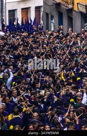 Turbas de Cuenca in purple robes make a deafening noise with their drums (tambores) and tin trumpets (clarines) at the head of the Camino del Calvario procession, which passes through Cuenca on Good Friday. Many people hit each other with crossed drumsticks and create the sound known as palilladas. Plaza Mayor, Cuenca, Castilla-La Mancha, Spain Stock Photo
