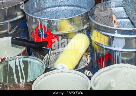 Empty paint buckets containing used rollers and brushes. Stock Photo