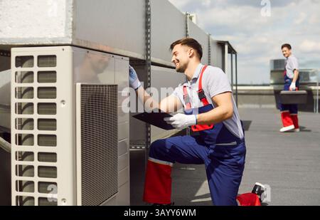 Happy smiling male worker technician installing, maintaining or repairing air conditioner. Stock Photo