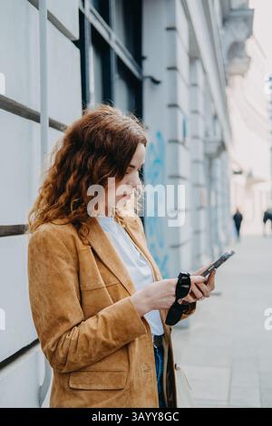 Young woman engaging with AI-powered mobile tools in an urban environment. Predictive tech, AI-enhanced user experience, and mobile-first habits.. Stock Photo