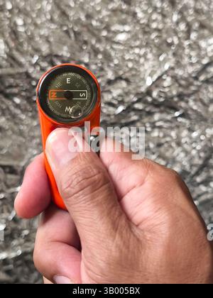 a hanging compass held in the right hand Stock Photo