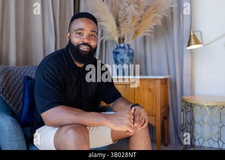 Relaxing African American man sitting on armchair at home, with dried pampas grass, copy space Stock Photo