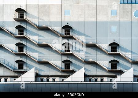 Modern building facade with repeating fire escape stair cast rhythmic shadow in the light Stock Photo