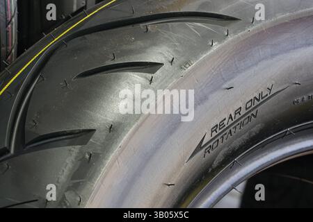 Close-up of the side of a new road motorcycle rear tire with the direction of rotation indicated, big motorbike wide rear tire Stock Photo