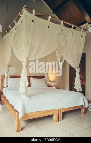 Traditional balinese cozy canopy bed in bedroom Stock Photo