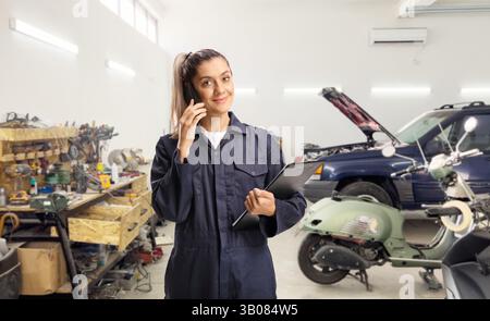 Female worker using a mobile phone in an auto repair shop Stock Photo