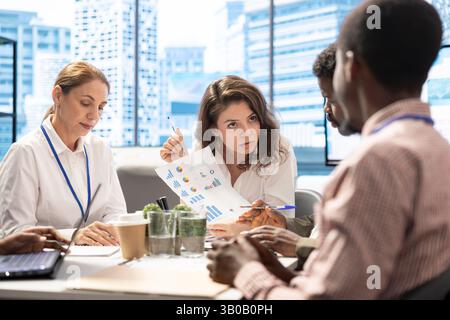 Business professionals using analytics reports on papers to review the progress, working together in increase sales for enterprise development. Staff present data driven insights to general manager. Stock Photo