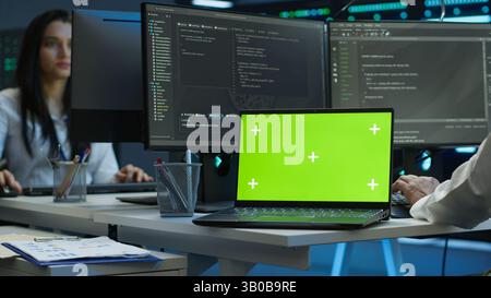 Admin in data center using isolated screen laptop to design, implement and manage gear, ensuring optimal performance and reliability. Expert in server room coding on chroma key notebook, camera A Stock Photo