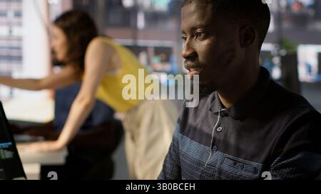 System administrator doing software quality assurance, checking source code on tablet. Close up of african american IT specialist at work inspecting coding on device, looking to fix errors, camera A Stock Photo