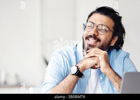 Pensive freelancer thinking about something while working on laptop at home office Stock Photo