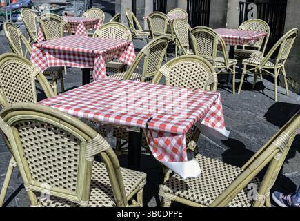 Newcastle, UK - Apr 13, 2025 - Empty tables and chairs covered red and white checkered tablecloths with chairs outside a cafe on street. Outdoor summe Stock Photo