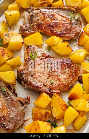 Pork chops and potatoes on a sheet pan oven roasted with herbs and spices for an easy dinner Stock Photo
