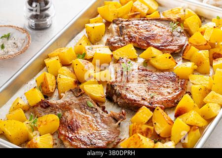 Pork chops and potatoes on a sheet pan oven roasted with herbs and spices for an easy dinner Stock Photo