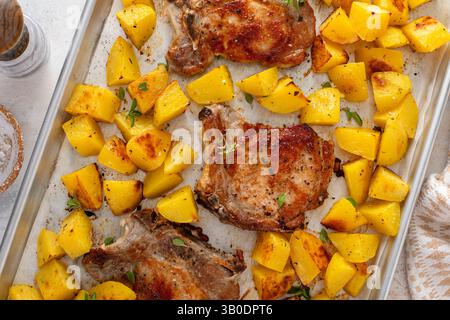 Pork chops and potatoes on a sheet pan oven roasted with herbs and spices for an easy dinner Stock Photo
