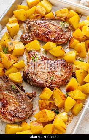 Pork chops and potatoes on a sheet pan oven roasted with herbs and spices for an easy dinner Stock Photo