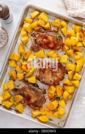 Pork chops and potatoes on a sheet pan oven roasted with herbs and spices for an easy dinner Stock Photo