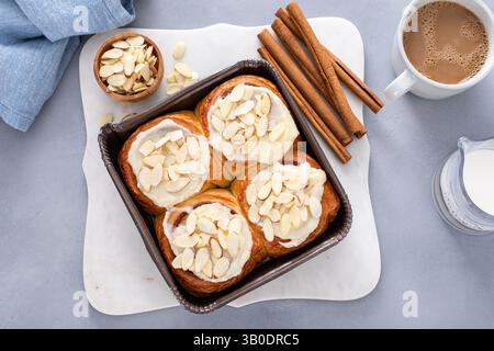 Cinnamon rolls topped with cream cheese frosting and sliced almonds, freshly baked and ready to eat Stock Photo