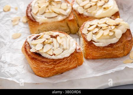 Cinnamon rolls topped with cream cheese frosting and sliced almonds, freshly baked and ready to eat Stock Photo