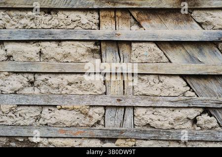 A textured wall with wooden strips against a rustic stone background, creating visual appeal Stock Photo
