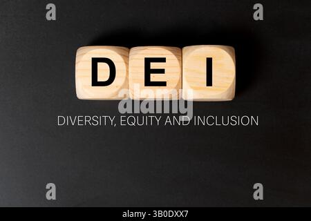 DEI letters written on three wooden cubes on black background, which means diversity, equity and inclusion. Stock Photo