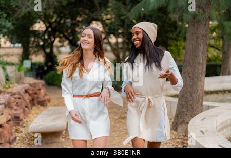 Two young women walking together and talking in a park Stock Photo