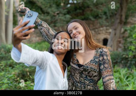 Two happy women taking a selfie with smartphone in a park Stock Photo