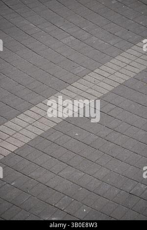 close up of a brick walkway on the ground with dark grey and light grey colored bricks rectangular lockstone  diagonal line dividing the two sections Stock Photo