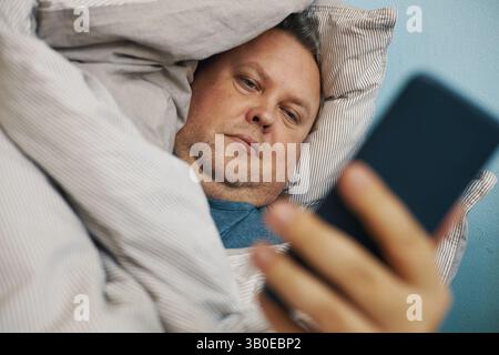 Relaxing in Bed While Using Smartphone Device Stock Photo