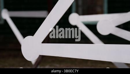 close up of white geometrical shapes of  bars with circles on the ends creating triangle shapes with black background empty framed space for type Stock Photo